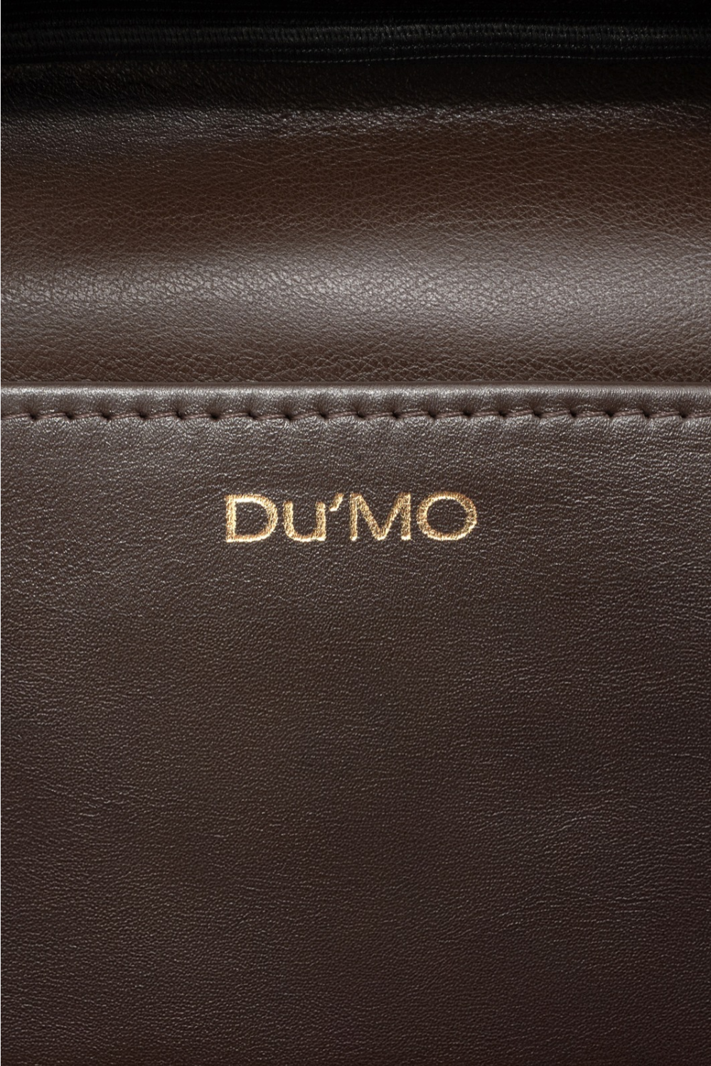 Du'Mo Poise Small Bag detail of the gold Du'Mo logo on brown leather. Independent Ukrainian designer at MIXMVSE London.