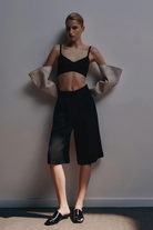 Ambitna black Bermuda shorts, knee-length tailored cut, styled look. Independent Ukrainian designer at MIXMVSE London.